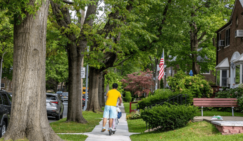 A man riding his bike down the sidewalk