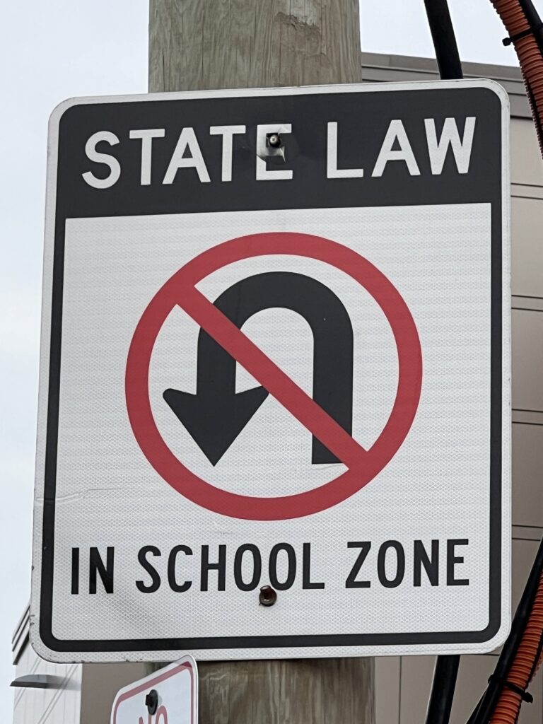 A sign that says state law in school zone.