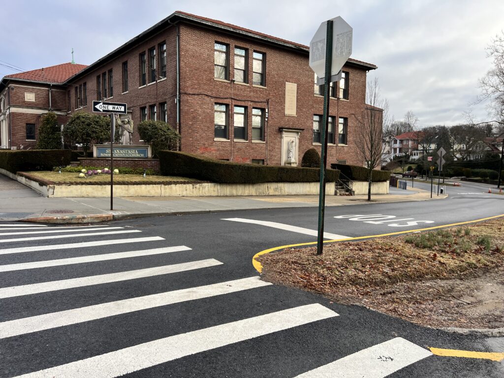 A street sign and crosswalk on the side of a road.